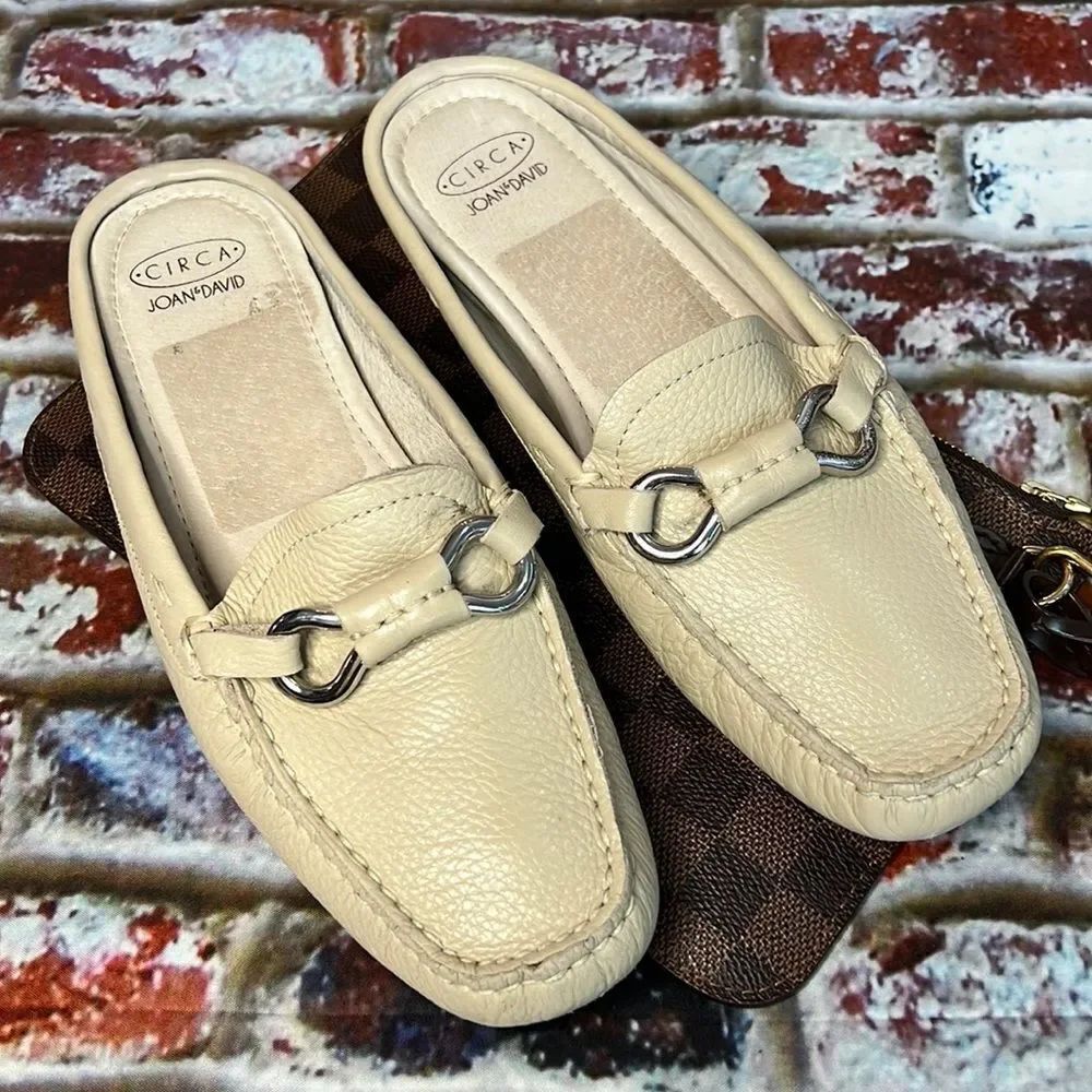 * Joan & David cream leather slides with silver buckle detail.